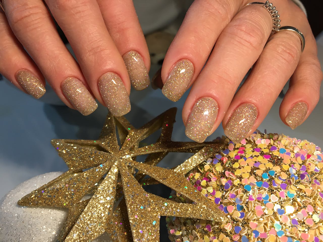 services-01 Elegant gold-glittered nails with star decorations, perfect for festive occasions.
