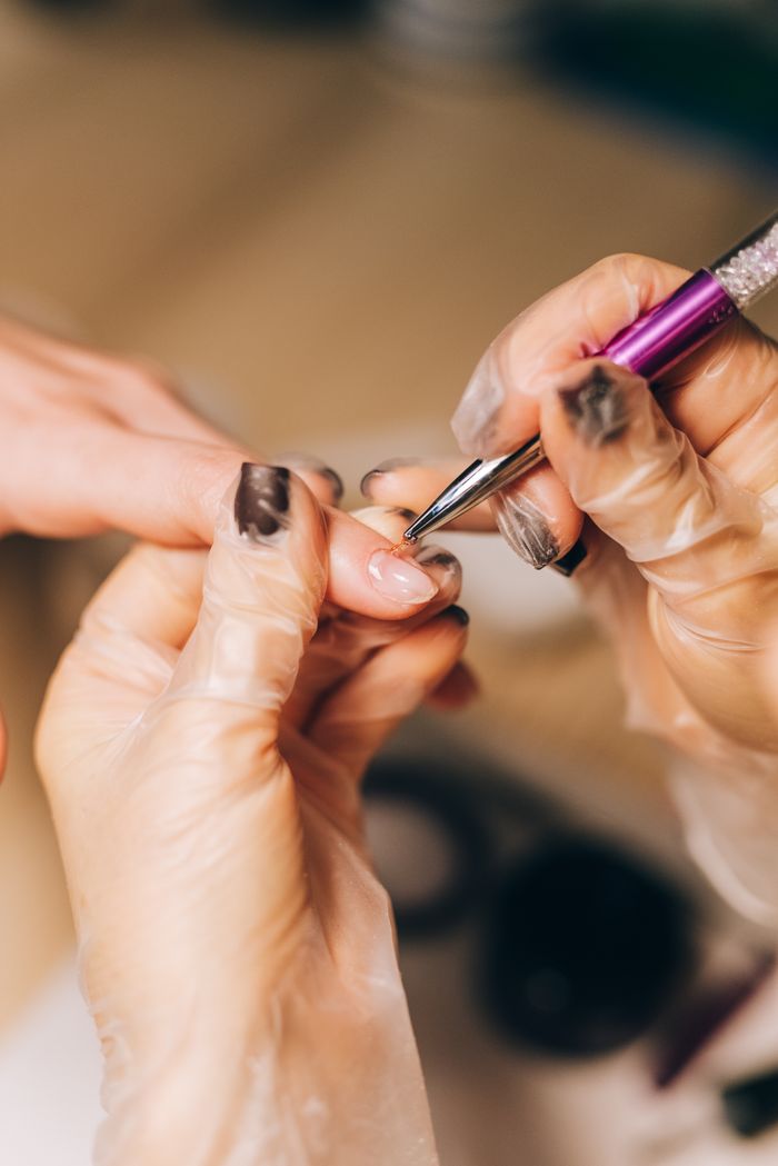 why-choose-us Close-up of a manicurist applying nail polish during a professional salon treatment.